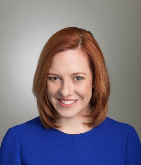 Jen Psaki in a blue top poses a picture.